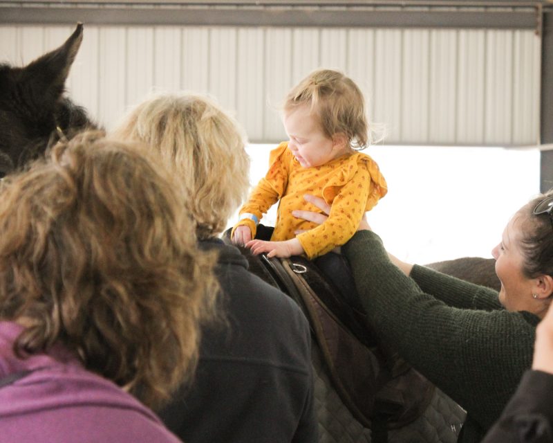 FBC EI student sits atop a horse while surround by staff.