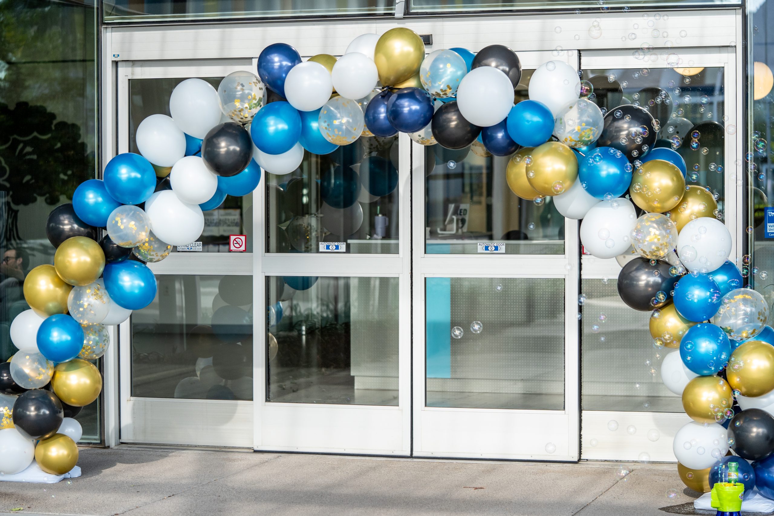 A blue, gold, and white balloon arch with sparkles at FBC's main campus.