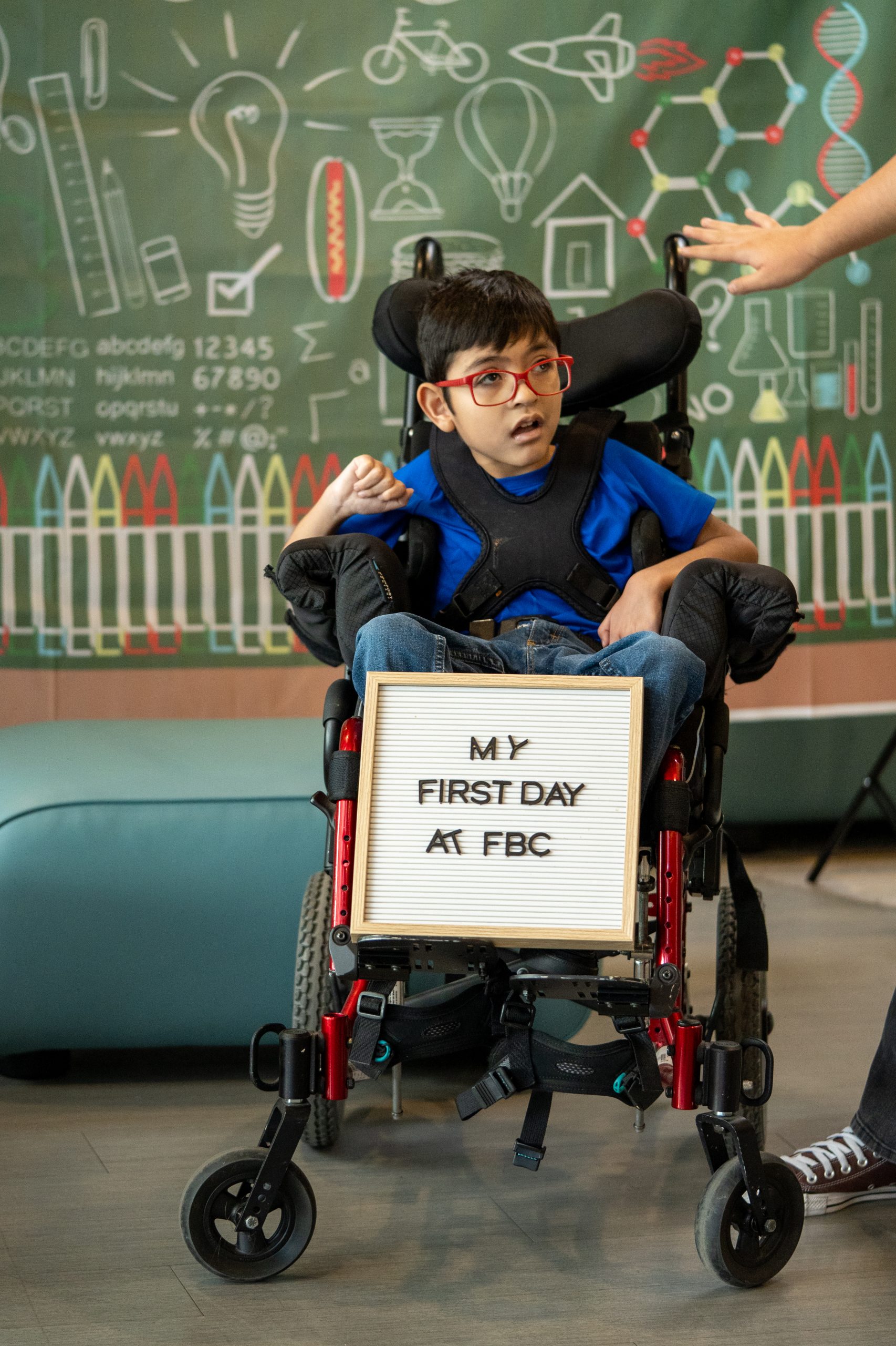 A young boy holds a board that says 'First Day at FBC.