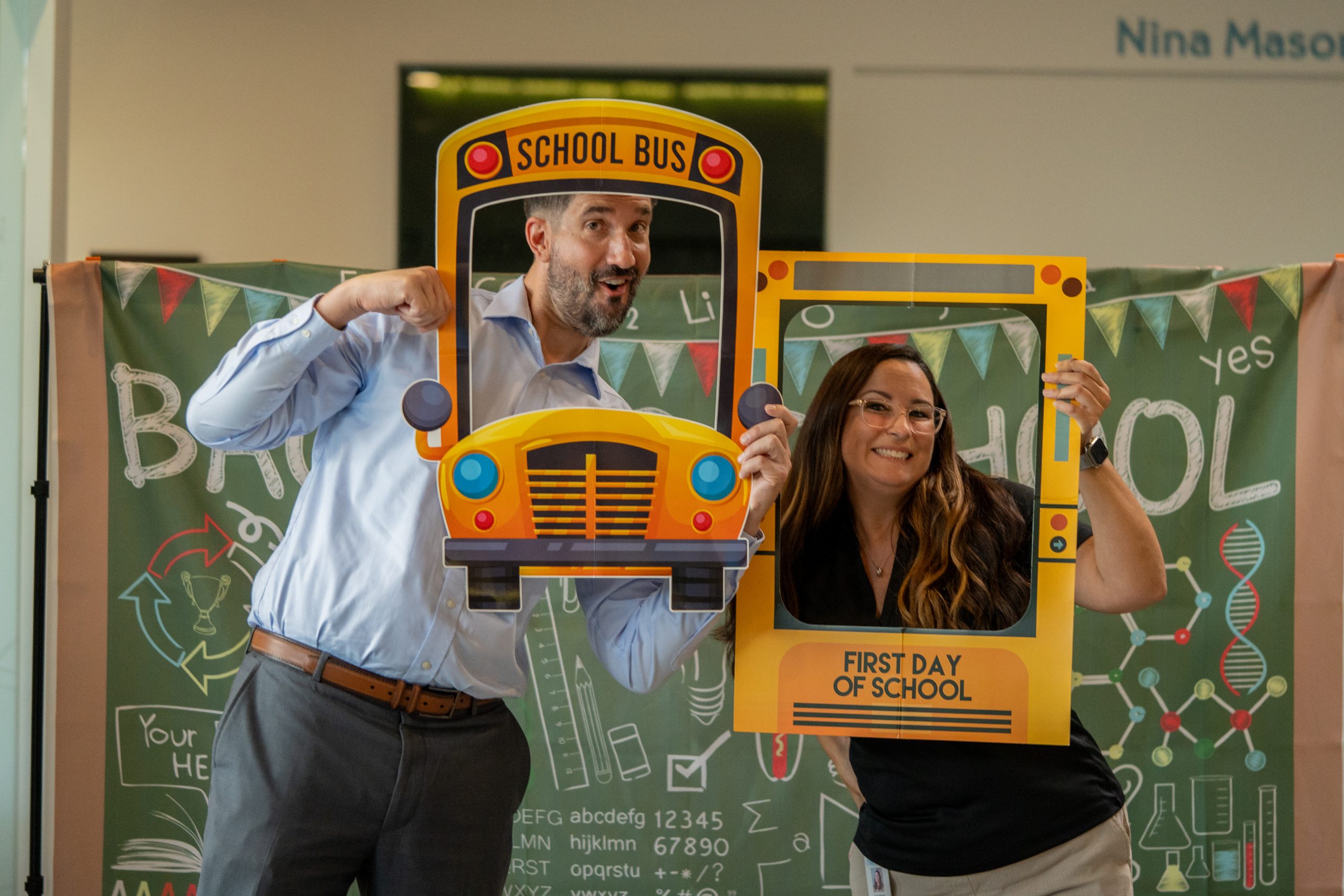 Jared Kittelson and our event manager smile as they pose with a school bus prop.